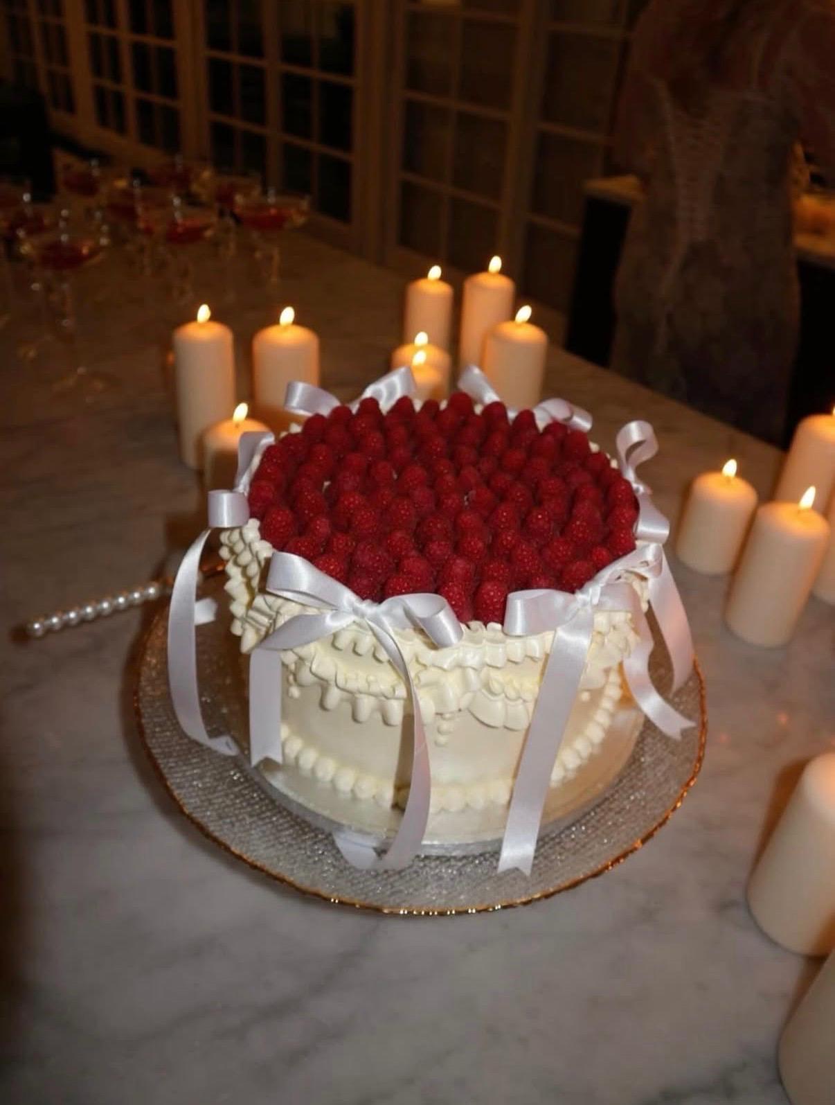 Bolo de framboesas com laços, rodeado de velas
