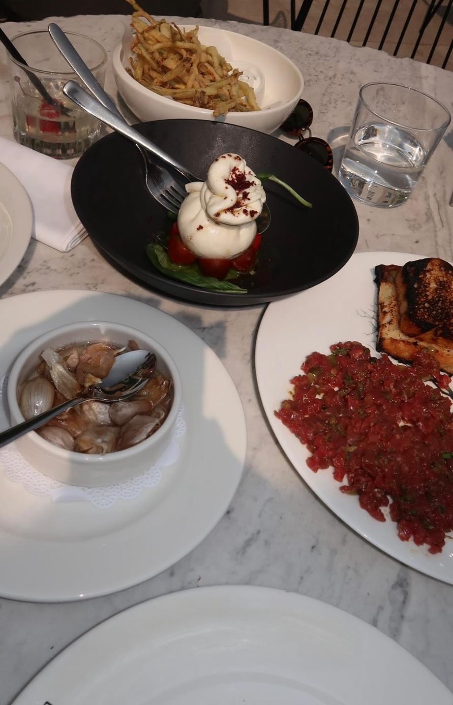 Burrata, tártaro e batata frita numa mesa de mármore